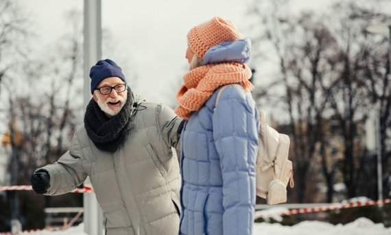 Älteres Paar geht im Schnee spazieren.