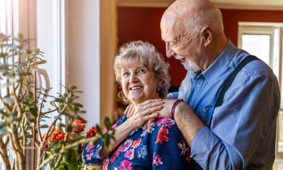 Ein Mann und eine Frau stehen an einem Fensterbrett mit Blumen.