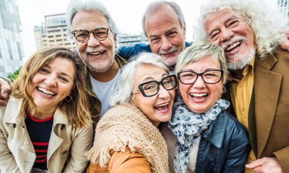 Sechs Personen, drei Männer im Hintergrund und drei Frauen im Vordergrund, haben sich in den Armen und lächeln in die Kamera.