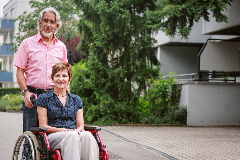 Ein Mann schiebt eine im Rollstuhl sitzende Frau.
