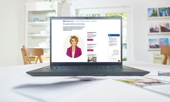 Ein Laptop auf einem Tisch, auf dem Bildschirm ist die Webseite Pflegeberatung.de mit dem Avatar des Chatbots Caro Compass zu sehen.