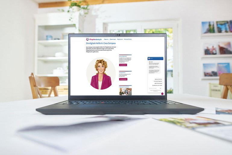 Ein Laptop auf einem Tisch, auf dem Bildschirm ist die Webseite Pflegeberatung.de mit dem Avatar des Chatbots Caro Compass zu sehen.