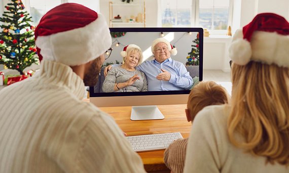 Eine junge Familie hält in der Weihnachtszeit eine Videokonferenz mit den Großeltern ab.