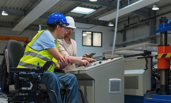 Mann mittleren Alters im Rollstuhl als Maschinenführer.